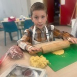 Alternatieve tekst: Jongetje in bakkerij met deeg en deegroller, leuk en leerzaam bakervaring.