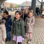 Gelukkige jonge kinderen genieten van buitenactiviteiten in schoolomgeving, met vriendelijke gezichten en kleurrijke kleding.